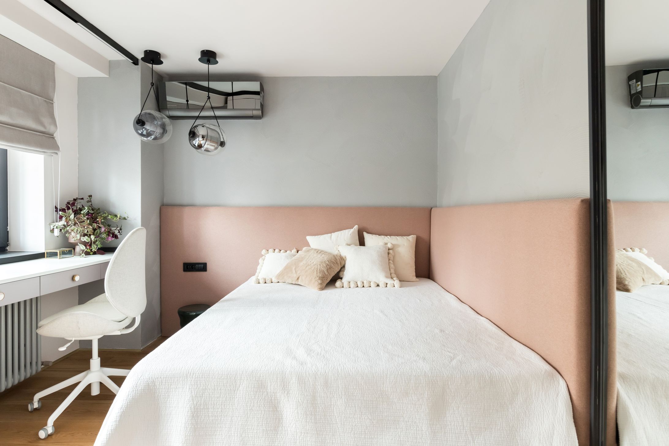 Dormitorul fetitei este simplu și discret, cu patul înconjurat pe două lături de o tăblie tapițată și o textura jucăușă de vopsea decorativă pe perete