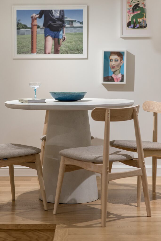 Masă de dining rotundă cu scaune din lemn și portret pictat pe perete, într-un apartament de artist